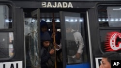 Pasajeros bajan de uno de los pocos buses en funcionamiento durante una huelga de transporte público. Los manifestantes rompieron los vidrios de la unidad por no acatar la medida. En Lima, Perú, el miércoles 23 de octubre de 2024. 