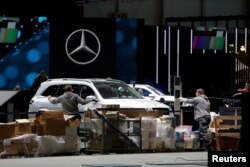 Cars and workers are pictured at the Palexpo exhibition center as the 90th edition of the International Motor Show is cancelled to curb the spread of the coronavirus, in Geneva, Switzerland, Feb. 28, 2020.