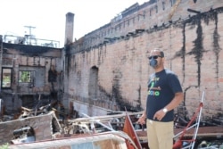 Ruhel Islam walks around the remains of the restaurant. (K. Khan/VOA)