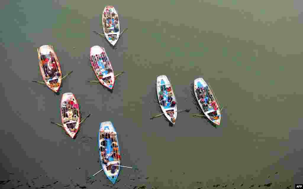 Indian Hindu pilgrims travel on boats to take a holy dip at Sangam, the confluence of the Rivers Ganges, Yamuna and the mythical Saraswati during the Maha Kumbh Mela in Allahabad, India.