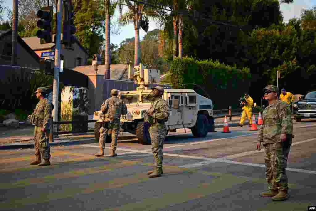 National Guard soldiers stand at a checkpoint to enter the Mandeville Canyon neighborhood of Los Angeles, California, Jan. 11, 2025, as the Palisades Fire continues to burn.