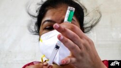 ভারতের কলকাতায় একটি ড্রাইভ-ইন টিকাদান কর্মসূচি চলাকালীন একজন স্বাস্থ্যকর্মী আস্ট্রাজেনেকা ভ্যাকসিনের সিরাম ইনস্টিটিউট অফ ইন্ডিয়ার সংস্করণ কোভিশিল্ড একটি সিরিঞ্জ প্রস্তুত করছেন। (ফটো-এপি/বিকাস দাস)