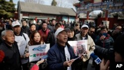 Relatives of passengers on board the missing Malaysia Airlines Flight 370 speak to journalists during a gathering outside the Yonghegong Lama Temple in Beijing on the two year anniversary, Tuesday, March 8, 2016.