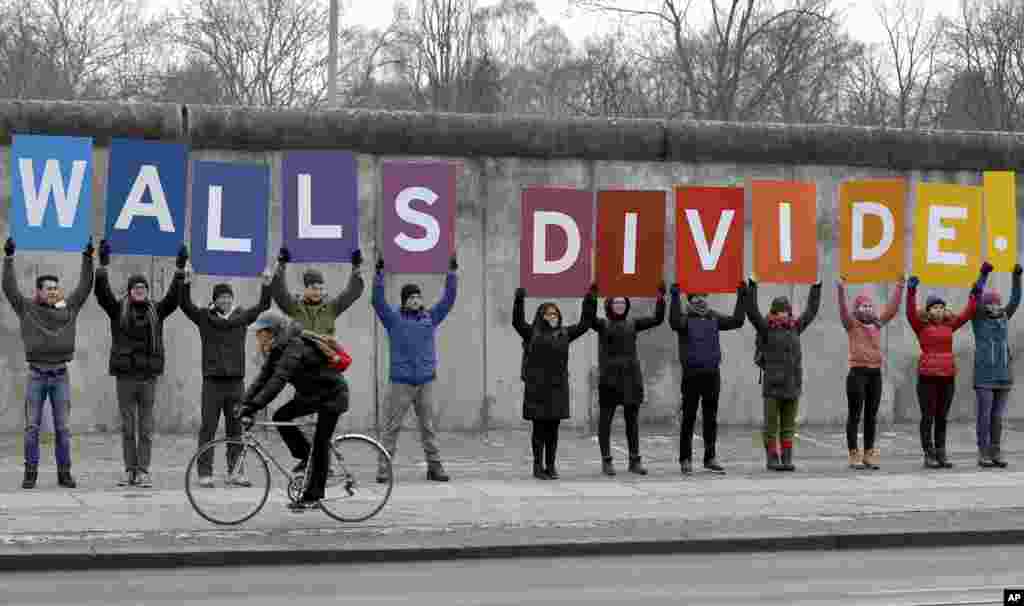 Protesters of the environmental organization Greenpeace display placards showing a part of a slogan at the Berlin Wall Memorial in Berlin, Germany, Friday, Jan. 20, 2017. Full slogan reads Mr. President, walls divide, build bridges!. U.S. President-elect Donald Trump will be inaugurated later the day