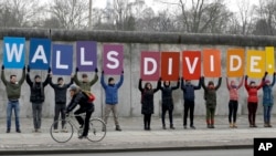 Des manifestants de l'organisation environnementale 'Greenpeace' avec des pancartes disant 'Les murs divisent', près du Mémorial du Mur de Berlin, en Allemagne, 20 janvier 2017