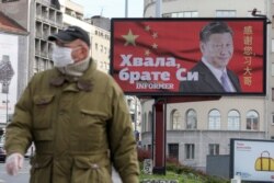 FILE - A man wearing a protective mask passes by a billboard depicting Chinese President Xi Jinping as the spread of the coronavirus disease continues in Belgrade, Serbia, April 1, 2020. The text on the billboard reads "Thanks, brother Xi".