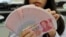 An employee counts Chinese yuan notes inside a bank in Taipei, February 6, 2013.