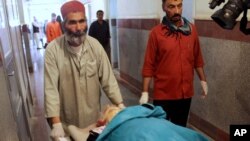 Afghan medical workers move the dead body of a foreign female aid worker who was employed by the International Assistance Mission, in Herat, west of Kabul, Afghanistan, July 24, 2014. 