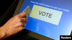 FILE - An elections official demonstrates a touch-screen voting machine at the Fairfax County Governmental Center in Fairfax, Virginia, Oct. 3, 2012.