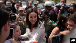 La candidata opositora María Corina Machado saluda a gente presente en su centro de votación en la primaria presidencial del domingo 22 de octubre de 2023, en Caracas.