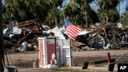 Sebuah bendera Amerika berkibar di tengah kehancuran kawasan permukiman akibat Badai Helene, di kota Jena, Florida, Minggu, 29 September 2024.