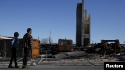 FILE - People stand outside the burned community center and apartments across the street from the Southern Baptist Church in Baltimore, Maryland, April 28, 2015.