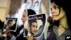 FILE - Egyptian journalists hold posters calling for the release from prison of photographer Mahmoud Abu Zeid, also known as Shawkan, in front of the Syndicate of Journalists building in Cairo, Egypt, Dec. 9, 2015.