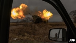 Фото: У дзеркалі автомобіля видно, як український військовий спостерігає за роботою шведської гаубиці Archer, яка веде вогонь по російських позиціях Росії в Донецькій області, 20 січня 2024 року. Фото: Roman PILIPEY/AFP