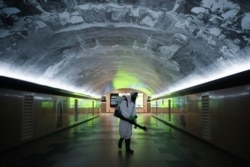 FILE - A sanitation worker disinfects an underpass at the central business district in the country’s main island Luzon to contain the coronavirus, in Makati City, Metro Manila, Philippines, March 17, 2020.