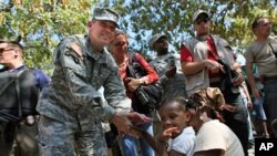 US Army special forces Lt. General Kenneth Keen (L) chats with a refugee family in a makeshift shelter camp near the Presidential palace in Port-au-Prince (File)