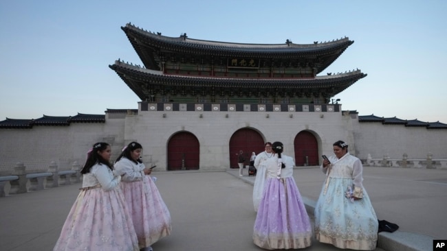 Jessica Hernández, tercera desde la derecha, de Estados Unidos, toma una foto cerca de Gwanghwamun, la puerta principal del Palacio Gyeongbok del siglo XIV, uno de los monumentos más conocidos de Corea del Sur, en Seúl, Corea del Sur, el 4 de diciembre de 2024.