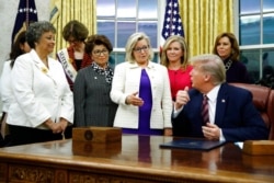 FILE - Rep. Liz Cheney, R-Wyo., center, speaks with President Donald Trump during a bill-signing ceremony for the Women's Suffrage Centennial Commemorative Coin Act in the Oval Office of the White House, Nov. 25, 2019.
