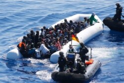 FILE - German Navy sailors and Finish Special Forces surround a boat with migrants near the German combat supply ship Frankfurt am Main during the EU's Operation Sophia, in the Mediterranean Sea, off the coast of Libya, March 29, 2016.