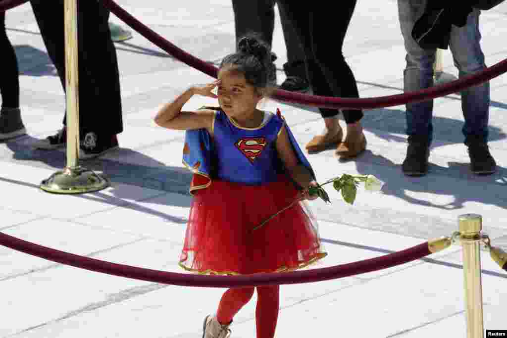 A child in a Supergirl costume pays respects to the late Justice Ruth Bader Ginsburg as her coffin lies in repose at the top of the front steps of the U.S. Supreme Court building, in Washington, D.C., Sept. 23, 2020.