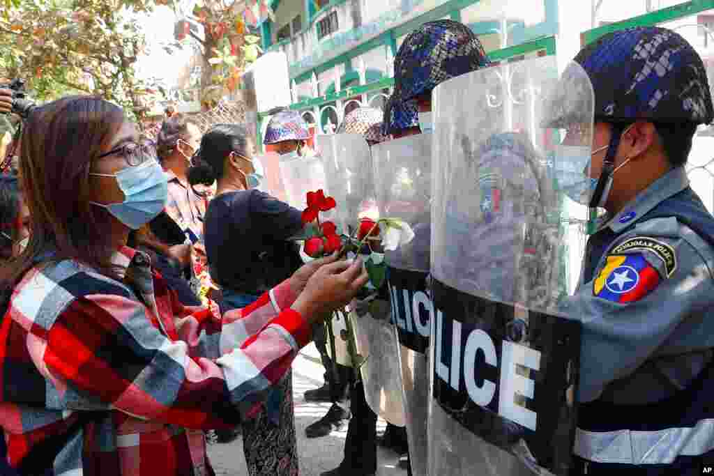 Supporters give roses to police while four arrested activists make a court appearance in Mandalay, Myanmar. Hundreds of students and teachers have taken to Myanmar's streets to demand the military hand power back to elected politicians.