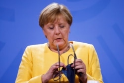 German Chancellor Angela Merkel holds a protective mask during a news conference on the current developments in Afghanistan, at the Chancellery in Berlin, Germany August 16, 2021 Odd Andersen/Pool via REUTERS