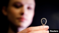 FILE - A model poses with The Farnese Blue diamond at Sotheby's auction house in London, Britain, April 6, 2018.
