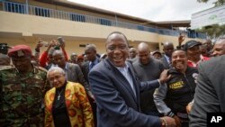 Kenya's President Uhuru Kenyatta shakes hands with supporters, accompanied by his wife, Margaret, center left, after casting his vote in Gatundu, north of Nairobi, Aug. 8, 2017.