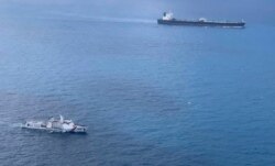 Dalam foto tak bertanggal yang dirilis oleh Badan Keamanan Laut Indonesia (BAKAMLA), sebuah kapal BAKAMLA mengawal kapal tanker MT Horse berbendera Iran (kanan atas) saat berlayar menuju Pulau Batam, Indonesia. (Bakamla via AP)