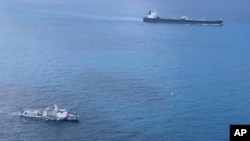 FILE - In this undated photo released by Indonesian Maritime Security Agency (BAKAMLA), a BAKAMLA ship escorts Iranian-flagged tanker MT Horse, top right, as they sail towards Batam Island, Indonesia.
