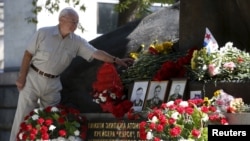 FILE - A man lays flowers during a commemoration ceremony at a monument for the Kursk nuclear submarine crew in Moscow, Russia, Aug. 12, 2015. 