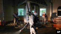 FILE - ervicemen of Belarus Ministry of Defence wearing protective gear disinfect a local hospital in the town of Zaslavl, outside the capital Minsk, Belarus, April 29, 2020