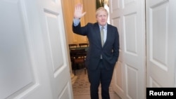 Britain's Prime Minister Boris Johnson waves as he is greeted by staff, arriving back at Downing Street, after meeting Queen Elizabeth and accepting her invitation to form a new government, in London, Britain December 13, 2019. Stefan Rousseau/Pool…