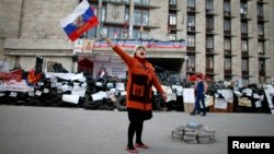 A pro-Russia protester shouts slogans as she waves a Russian flag outside a regional government building in Donetsk, in eastern Ukraine April 23, 2014. 