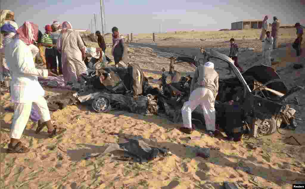 People check the scene where a car bomb exploded in near the port town of El-Arish in Egypt's Sinai peninsula, July 24, 2013. 