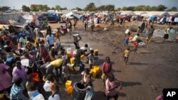 In this file photo of Sunday Dec. 29, 2013 file photo, displaced people gather around a water truck to fill containers at a United Nations compound which has become home to thousands of people displaced by the recent fighting, in the capital Juba, South Sudan. One year after mass violence broke out in South Sudan, battles between government forces and rebel fighters continue, and aid officials say the international community must help residents stave off mass hunger.(AP Photo/Ben Curtis, File)