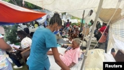 Uma mulher recebe assistência médica fora do hospital, sábado, depois do terramoto de 7.2 em Les Cayes, Haiti, 16 de Agosto, 2021.