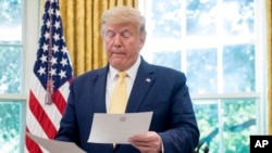 FILE - President Donald Trump is seen holding documents in the Oval Office of the White House, in Washington, Oct. 11, 2019. 