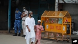 Indian para-military force soldiers stand guard as Indian Muslims walk past closed shops on Eid al Adha following Covid pandemic restrictions, in New Delhi, India, Wednesday, July 21, 2021. Muslims worldwide marked the the Eid al-Adha holiday over…