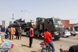FILE - Bystanders look on as a tank is transported on a truck through the streets of N'Djamena, Chad, Jan. 3, 2020, as Chadian troops return from a mission fighting Boko Haram in neighboring Nigeria.