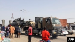 Des passants regardent un char transporté par camion dans les rues de N'Djamena, Tchad, le 3 janvier 2020