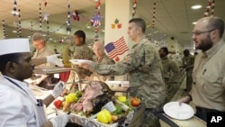 A dining facility worker, left, serves soldiers and civilians for their Thanksgiving meal at the U.S.-led coalition base in Kabul, Afghanistan, November 22, 2012. 