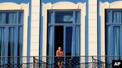 FILE - A tourist looks out from his hotel room's balcony in Havana, Cuba.