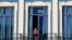 FILE - A tourist looks out from his hotel room's balcony in Havana, Cuba.