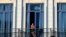 FILE - A tourist looks out from his hotel room's balcony in Havana, Cuba.
