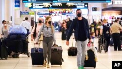 Holiday travelers push their luggage inside Miami International Airport, Tuesday, Nov. 23, 2021, in Miami. (AP Photo/Marta Lavandier)