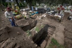 A worker digs graves in the COVID-19 section of a cemetery on the outskirts of Mexico City, Sept. 1, 2020.