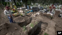 A worker digs graves in the COVID-19 section of a cemetery on the outskirts of Mexico City, Sept. 1, 2020.