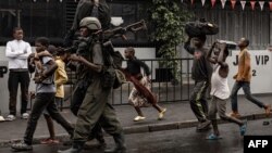 A member of the M23 armed group walks alongside residents through a street of the Keshero neighborhood in Goma, on Jan. 27, 2025.