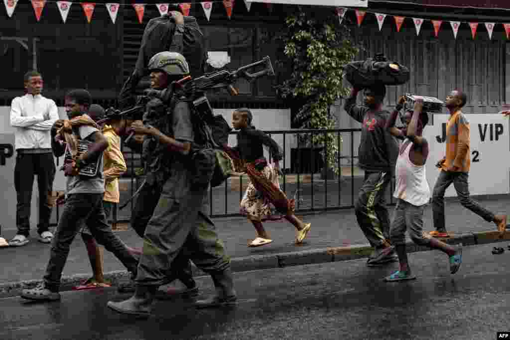 A member of the M23 armed group walks alongside residents through a street of the Keshero neighborhood in Goma, on Jan. 27, 2025.